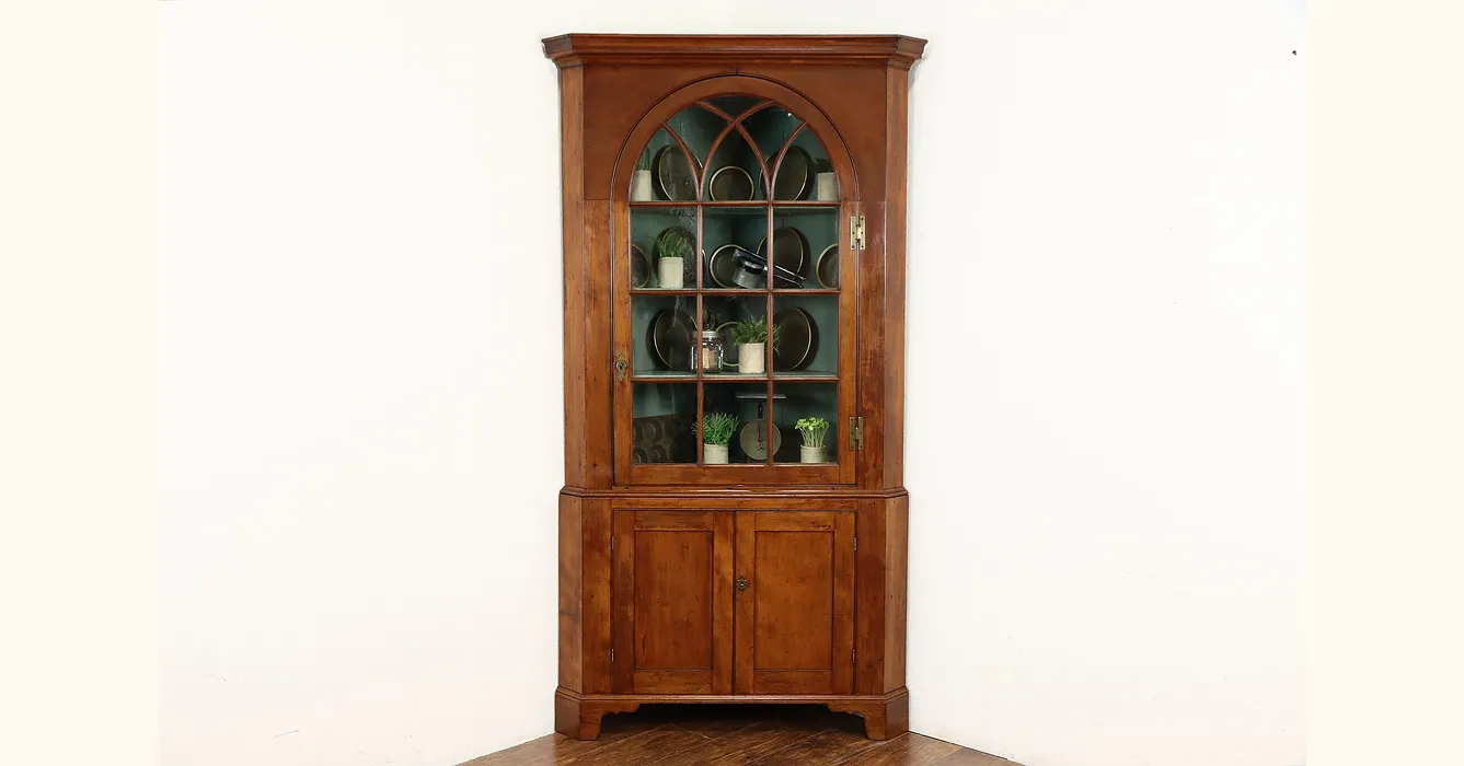 Antique corner cupboard beside arched Gothic window in country